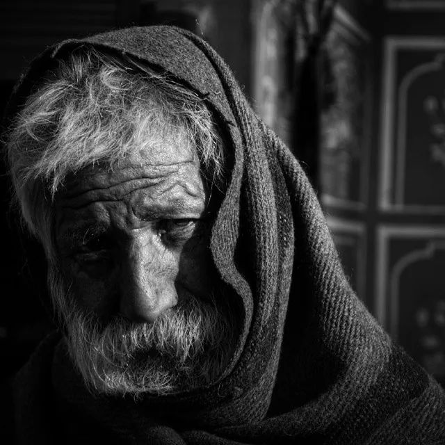 Black-and-white portrait of an old man with a white beard wrapped in a shawl, 2014