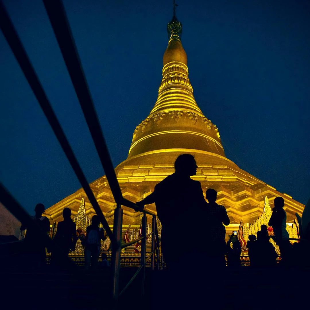 Silhouettes of pilgrims leaving the golden pagoda in Mumbai after sunset, 2016